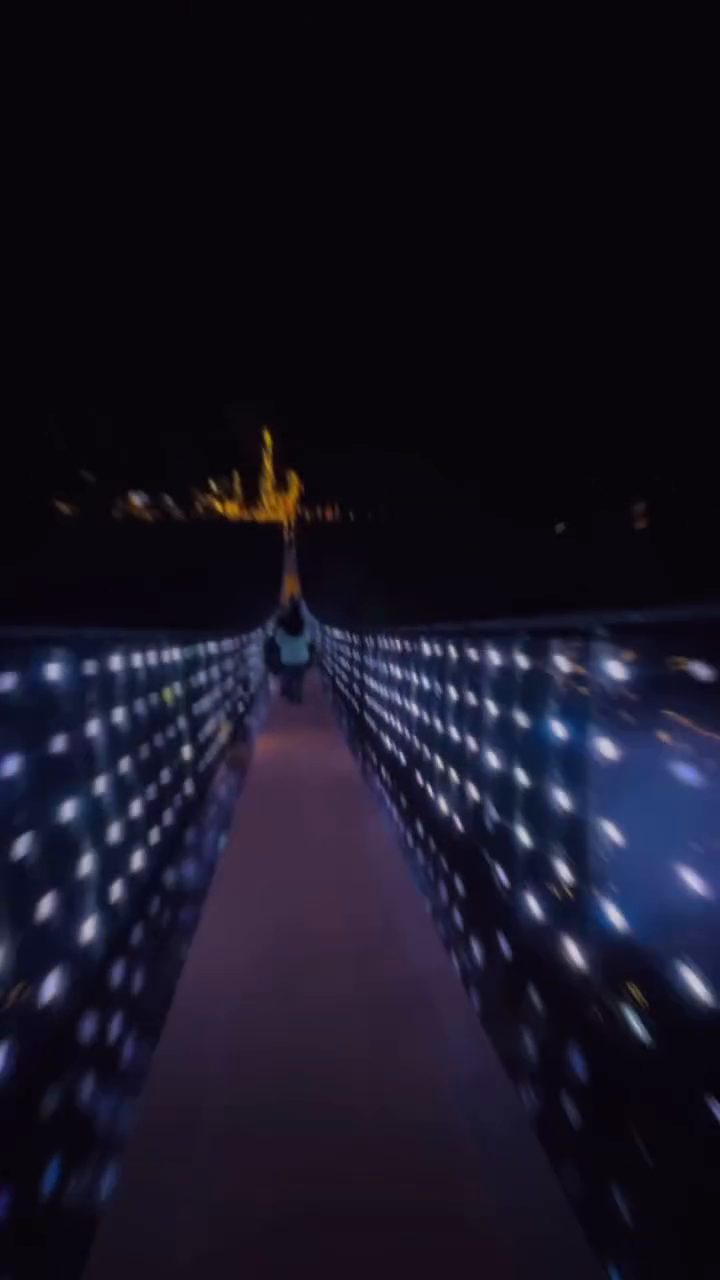 A suspension bridge lined with white lights at night